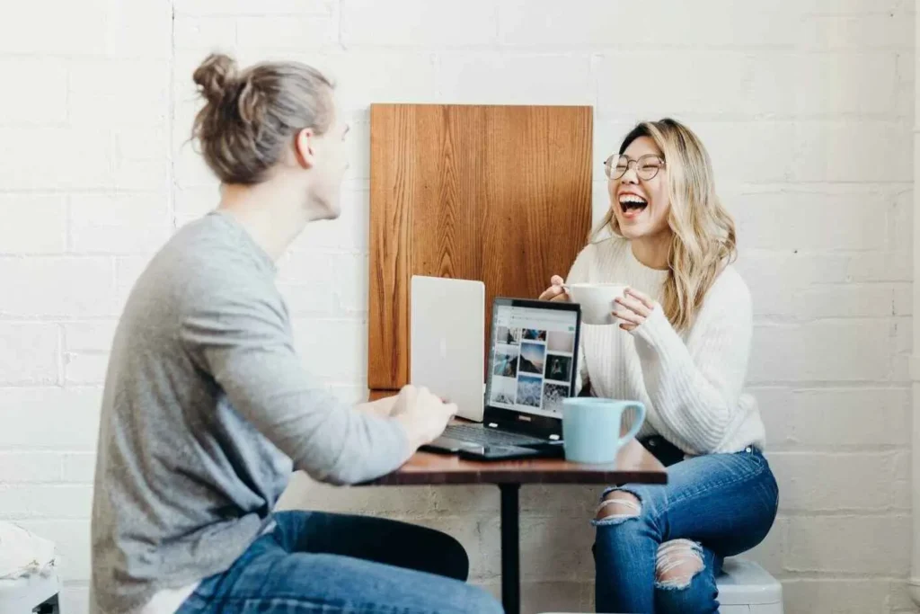 2 People having a coffee at a desk with a laptop discussing the best digital marketing company for small businesses'